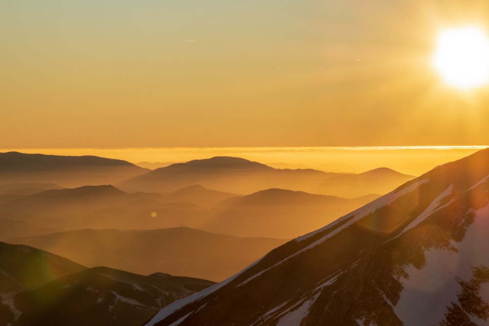 the sun is setting over a mountain range