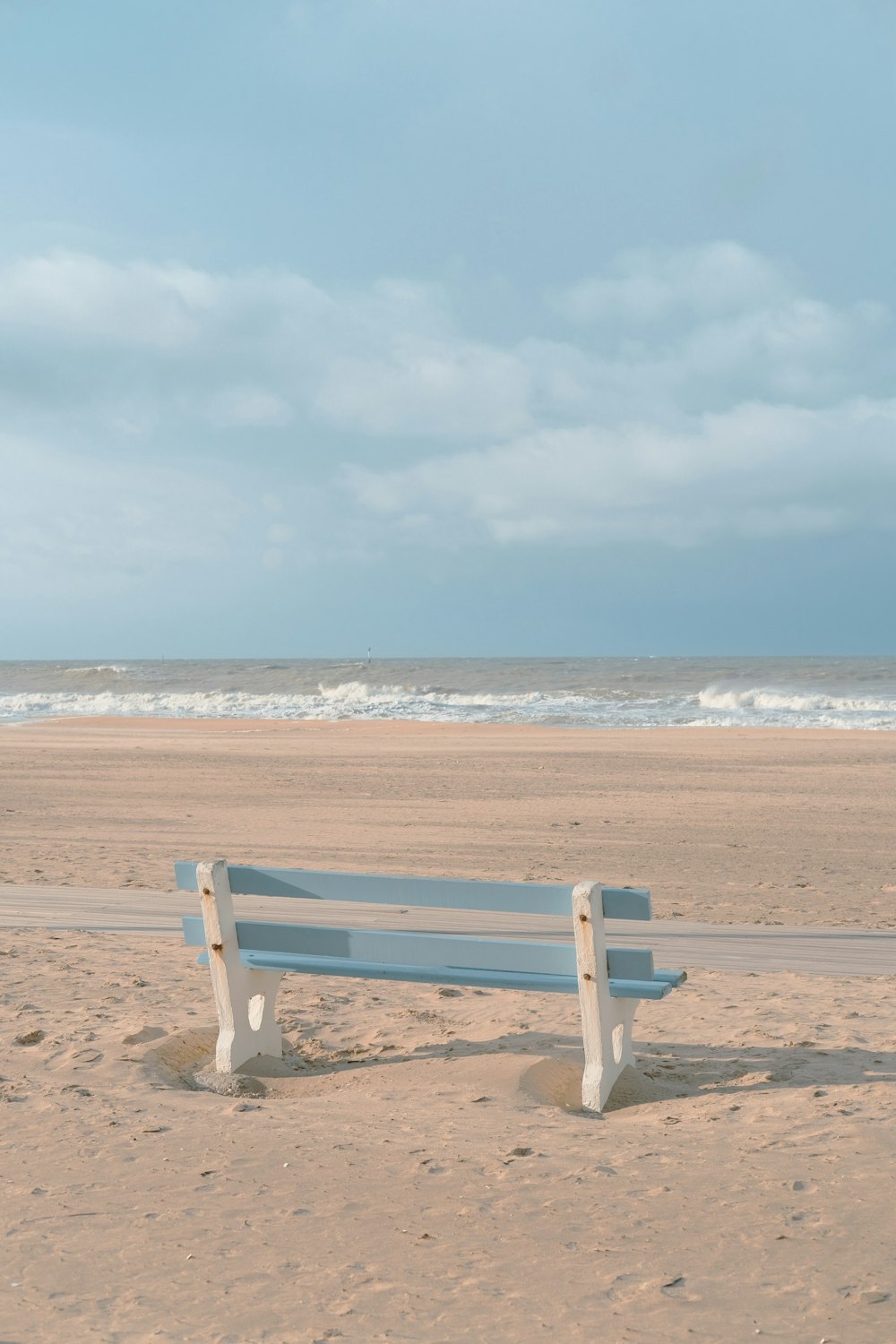 a white bench sitting on top of a sandy beach
