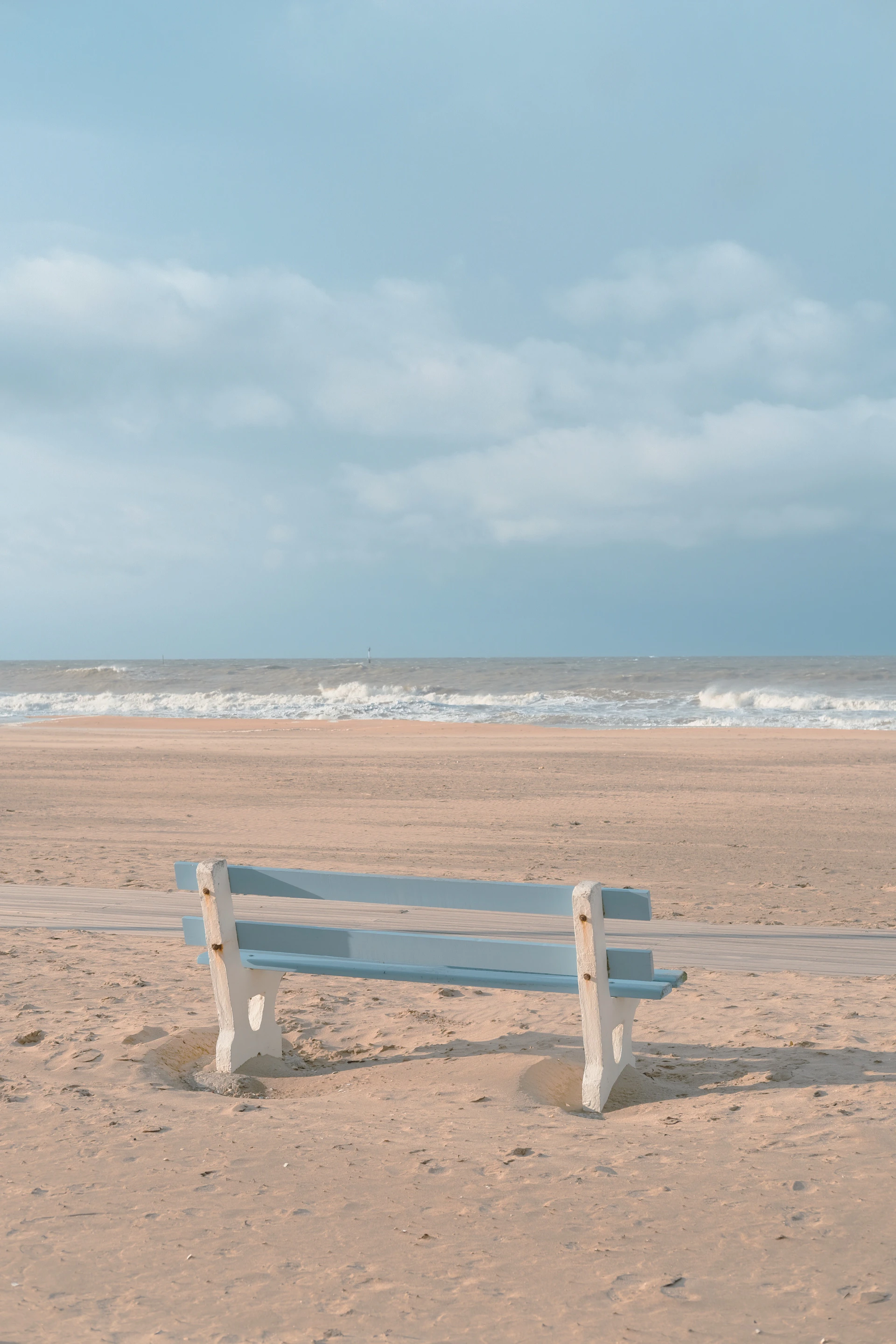 a white bench sitting on top of a sandy beach