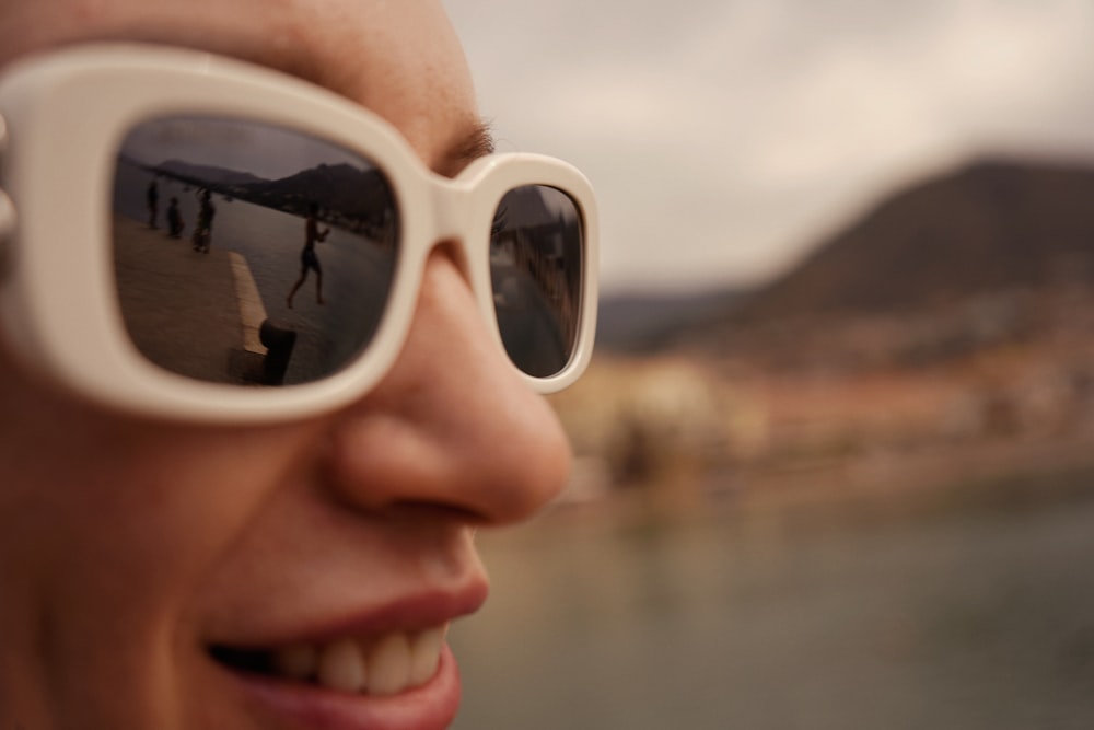 a woman wearing sunglasses with a reflection of a skateboarder