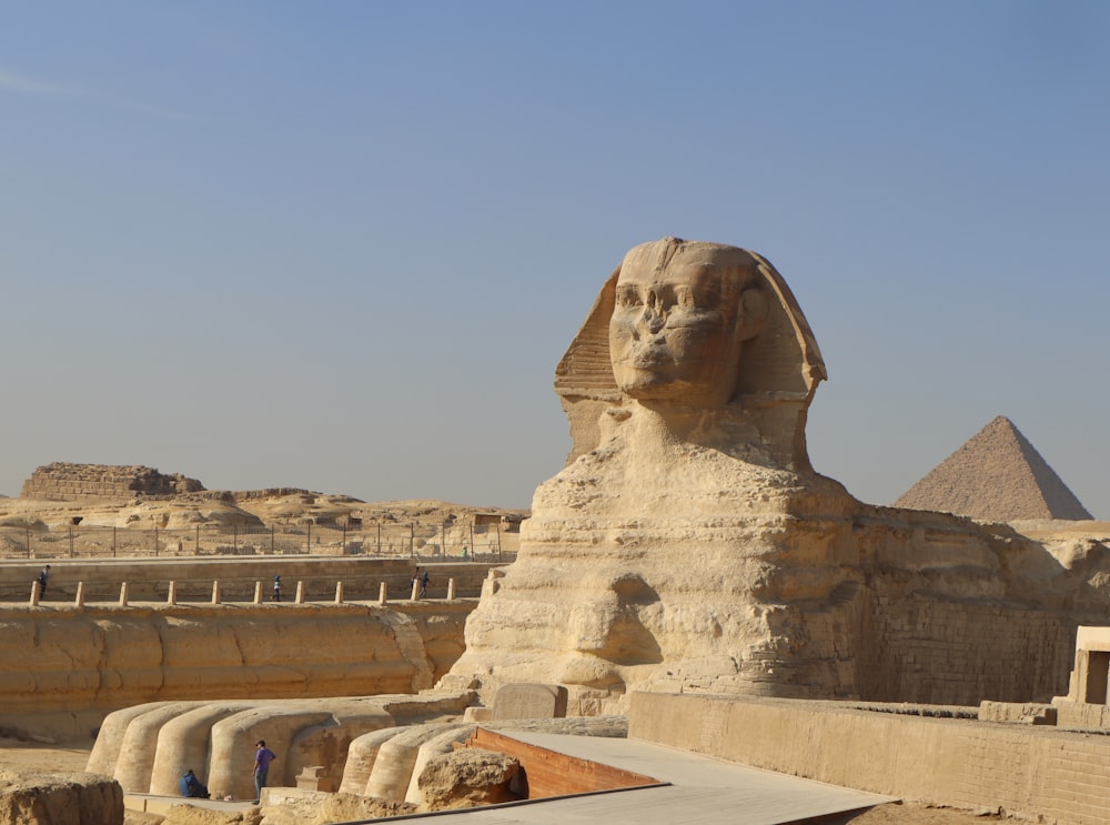 Una gran estatua de esfinge frente a una pirámide