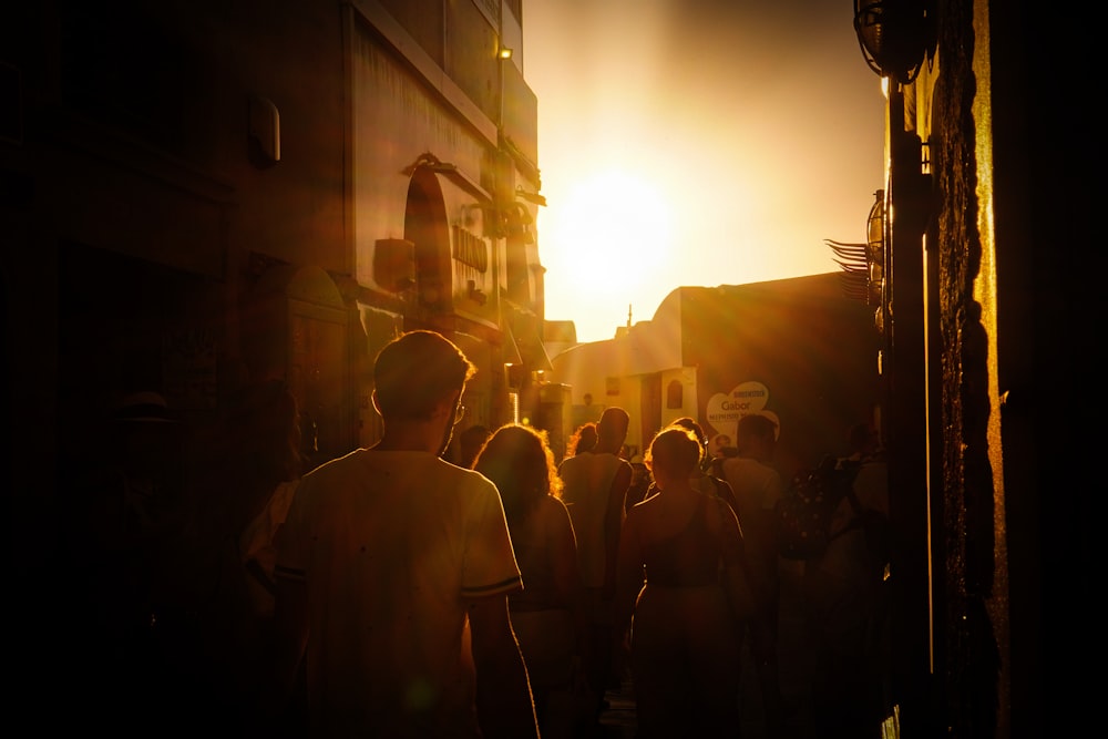 a group of people walking down a street at sunset