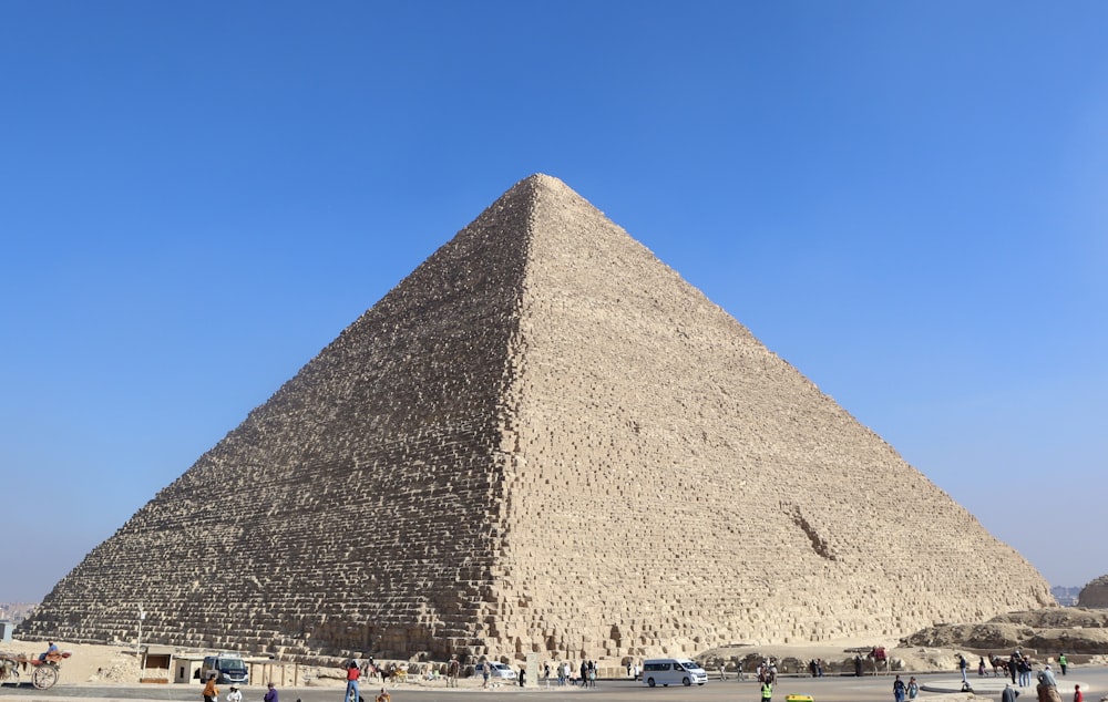 a group of people standing in front of a large pyramid