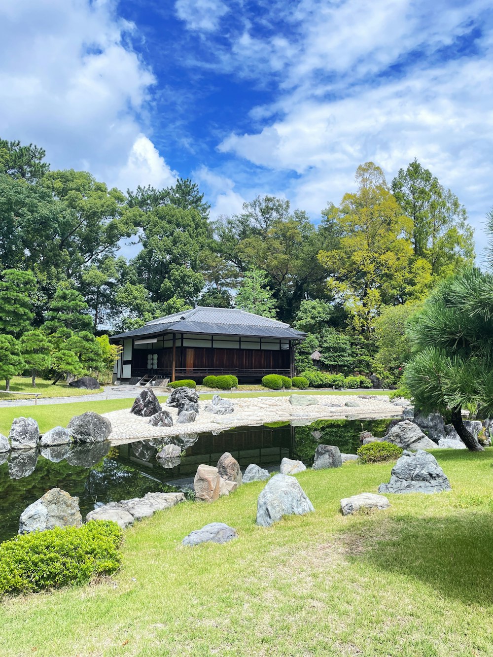 a gazebo in a park with a pond and rocks
