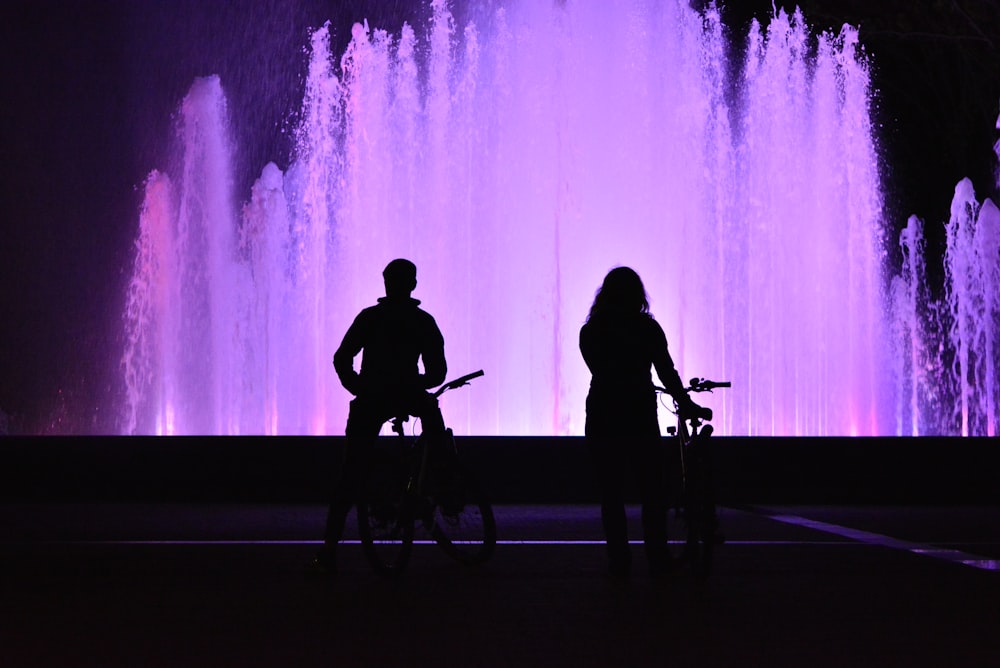 a couple of people standing in front of a water fountain