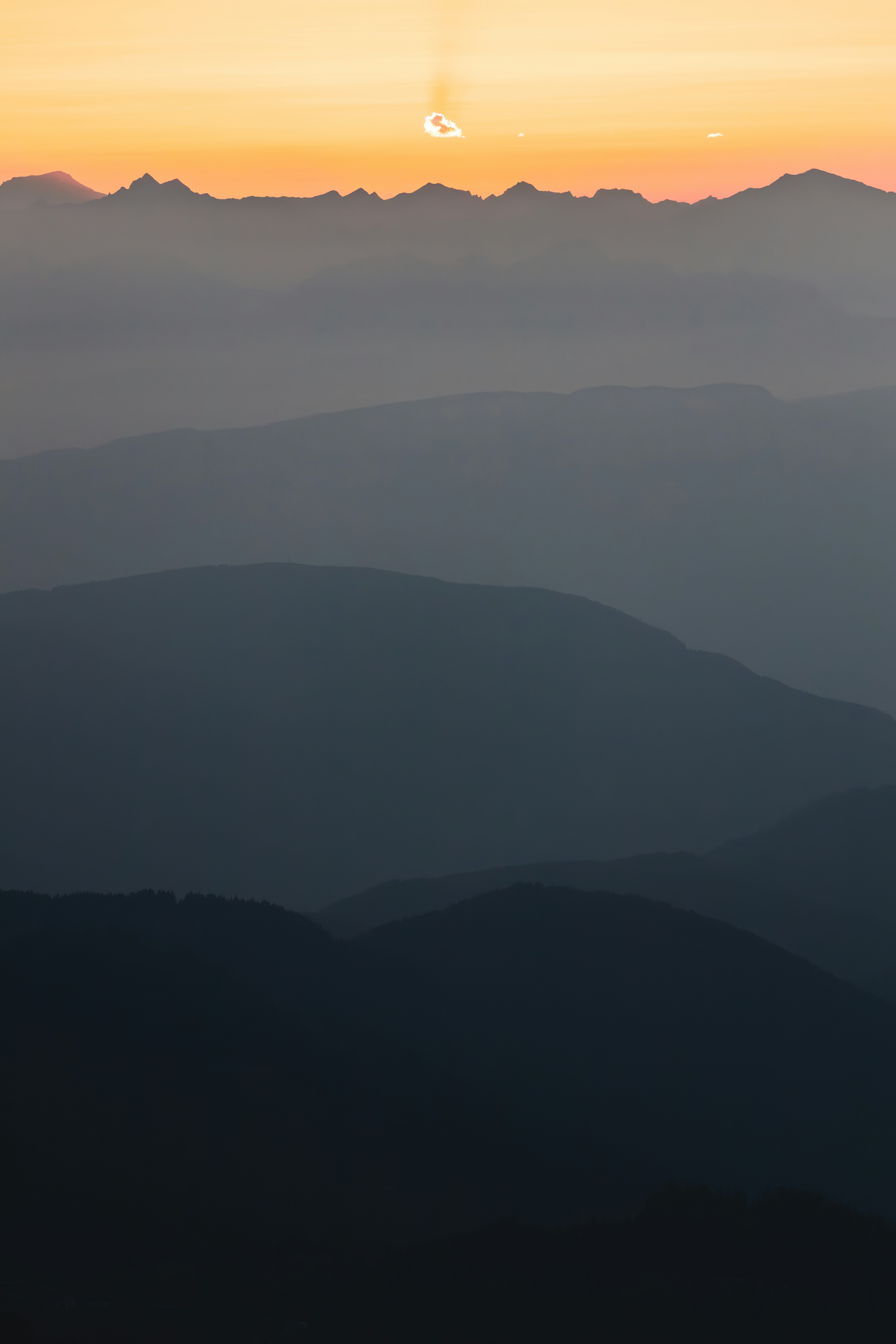 the sun is setting over the mountains in the distance