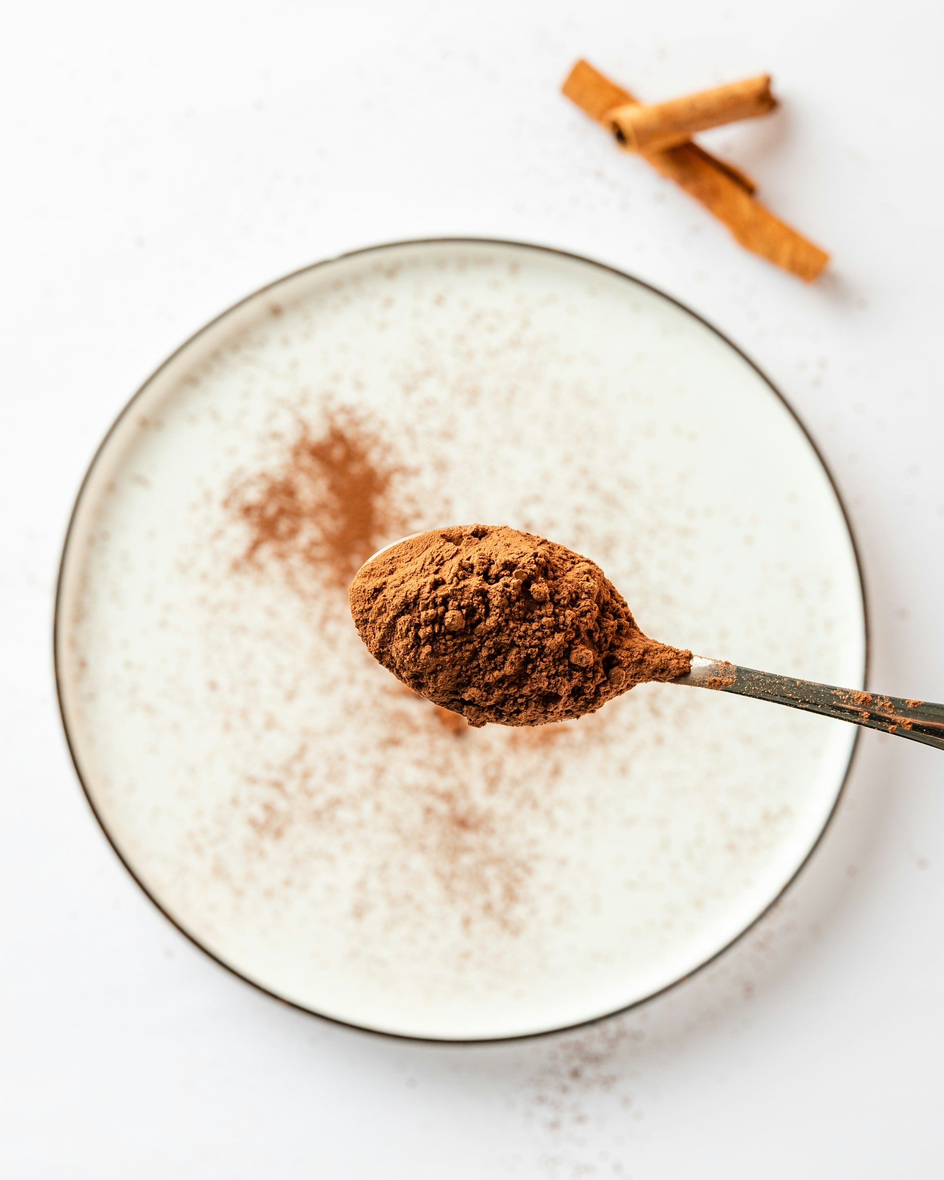 a spoon full of cocoa powder and cinnamon sticks