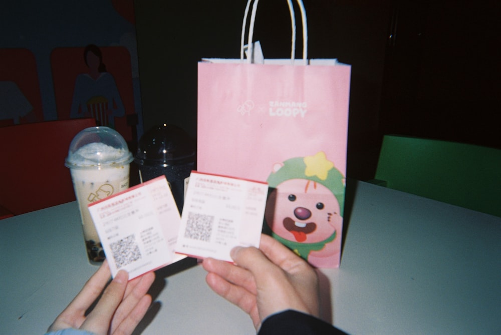 a person holding a pink shopping bag and some cards