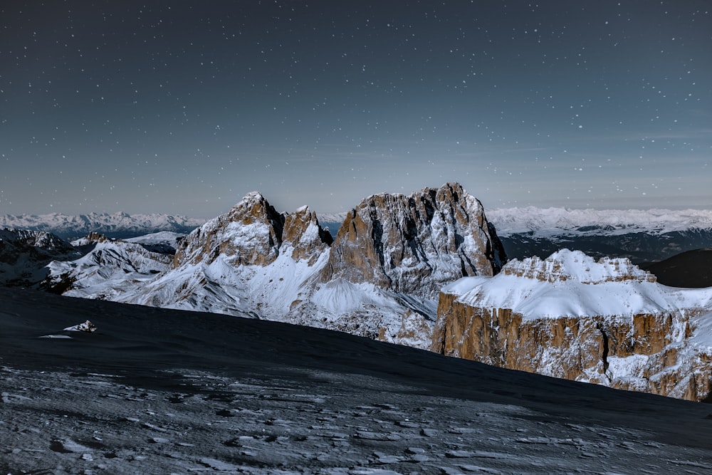 a snow covered mountain range under a night sky