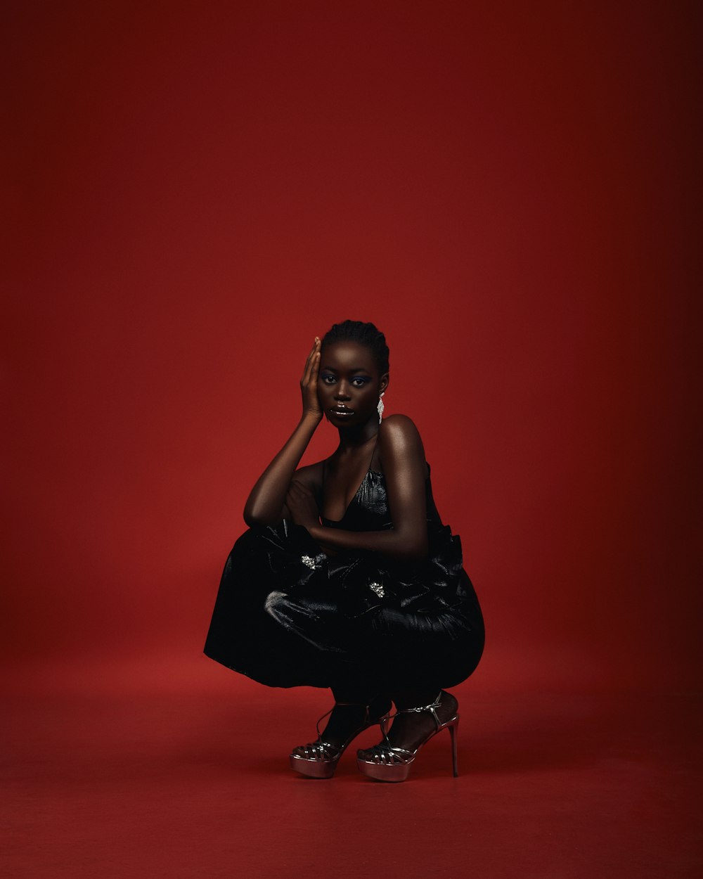 a woman in a black dress kneeling on a red background