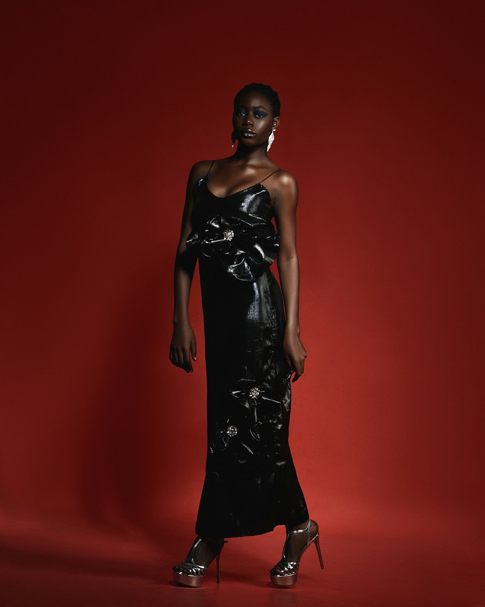 a woman in a black dress standing in front of a red background