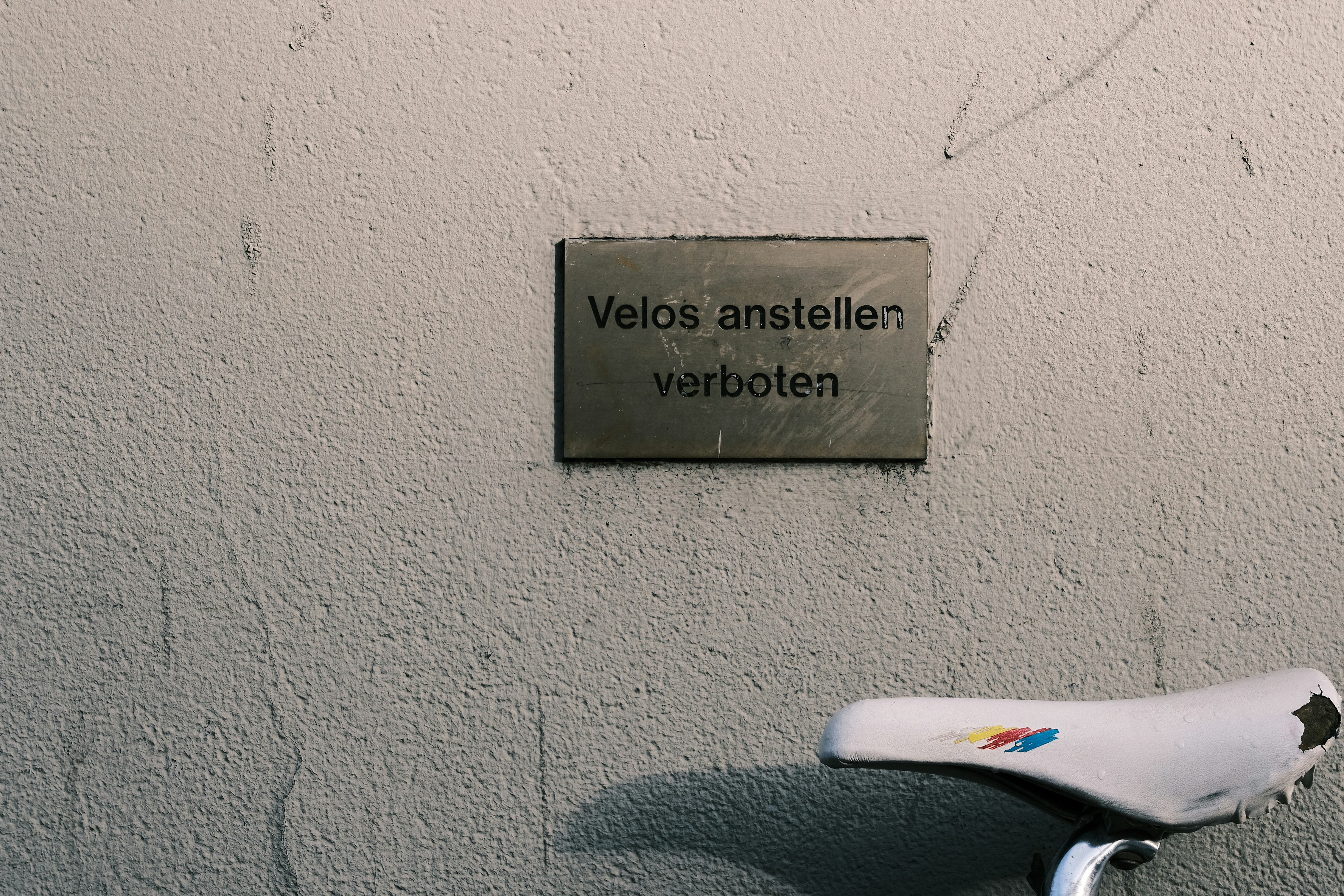 a bicycle parked next to a wall with a sign on it