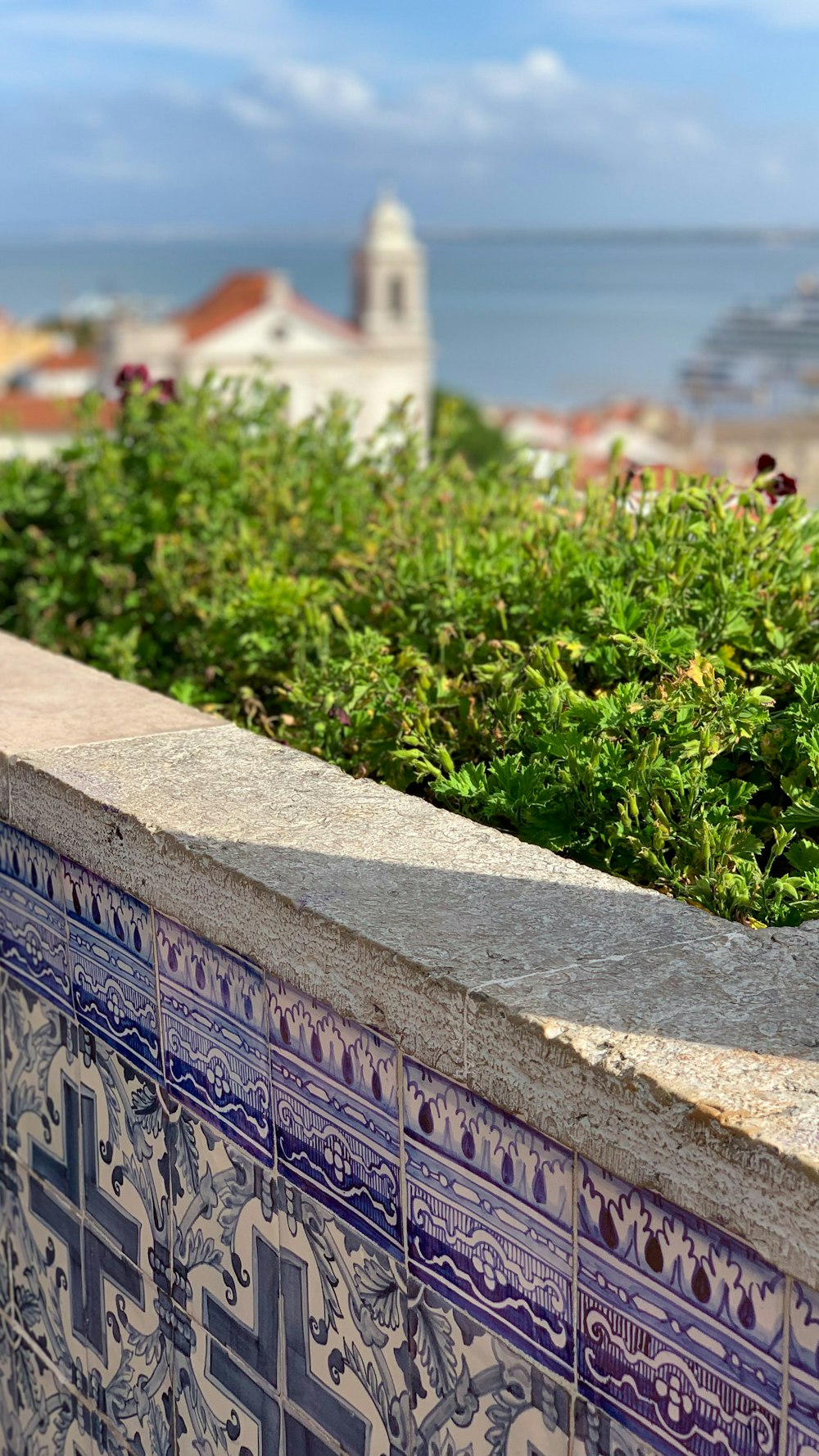 a blue and white tile wall with a clock tower in the background