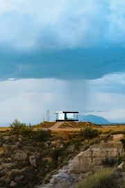 a small building on a hill with a sky background