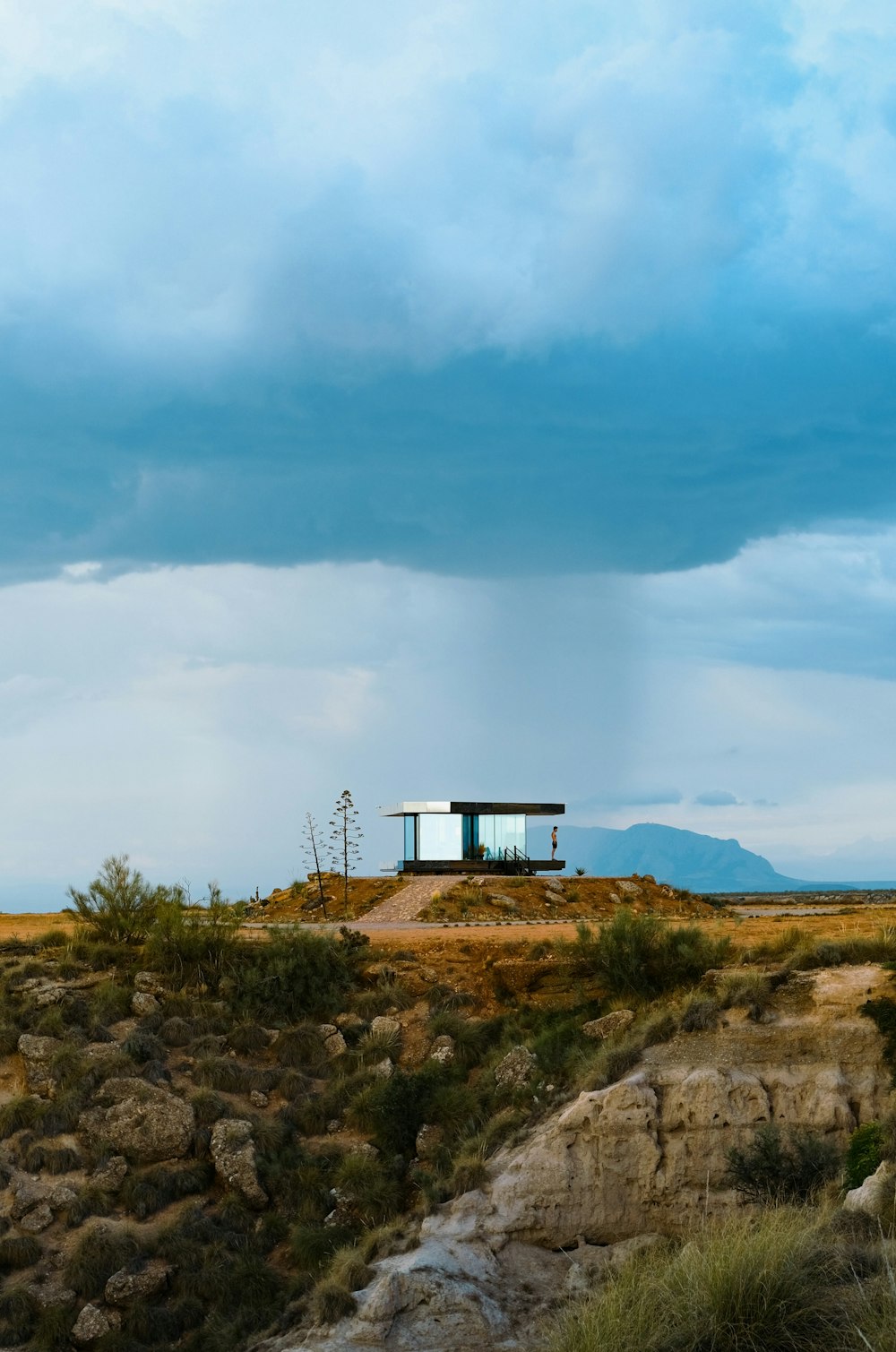 a small building on a hill with a sky background