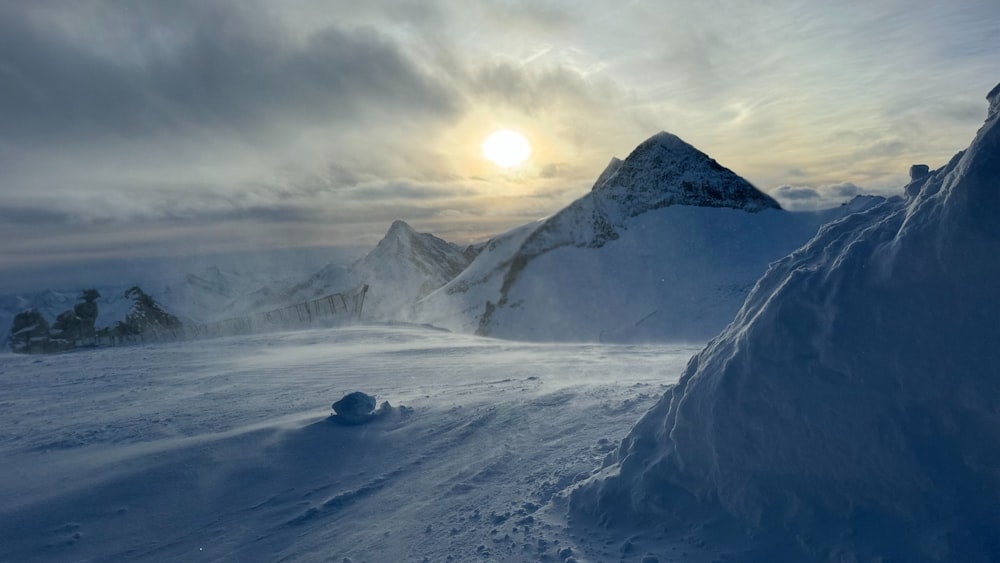 the sun is setting over a snowy mountain