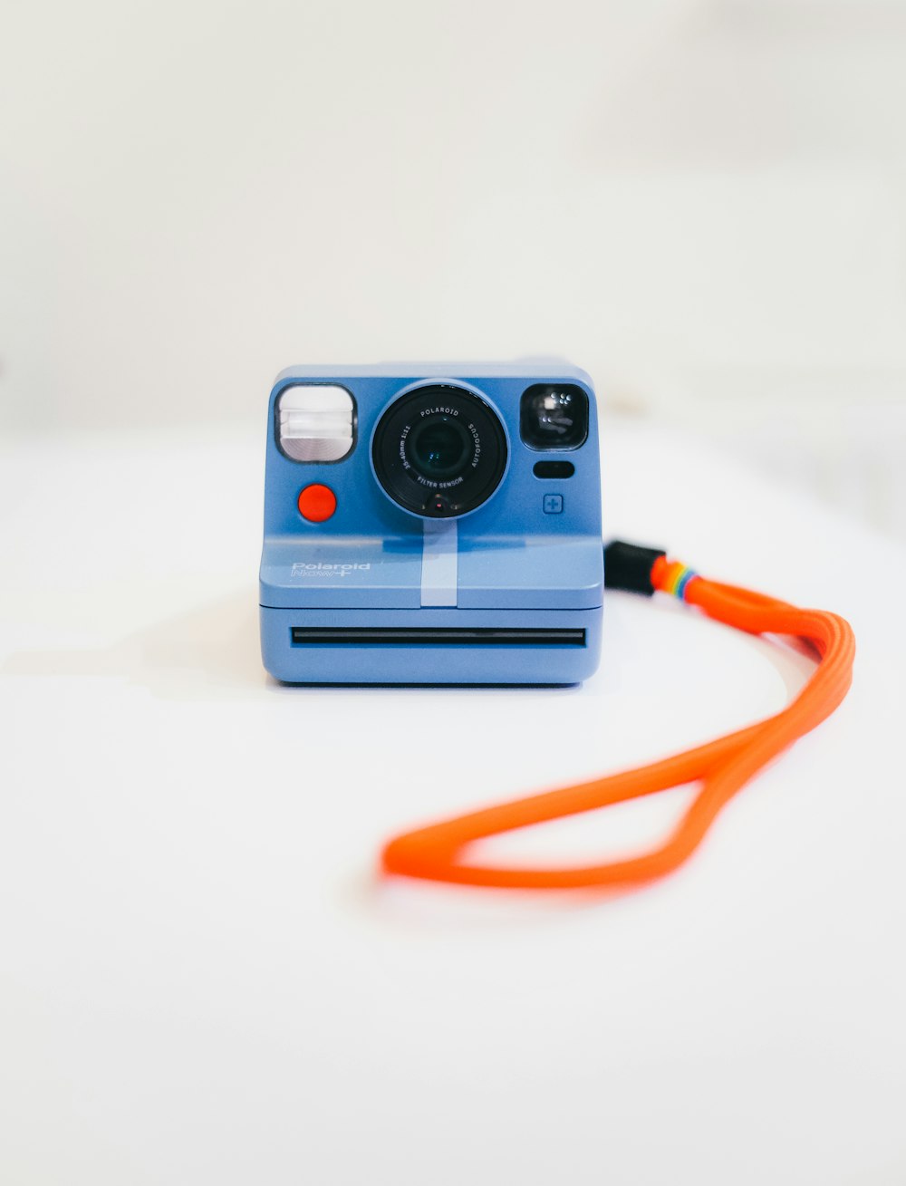 Uma câmera polaroid azul com um cordão laranja