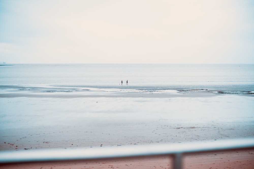 two people standing on a beach near the ocean