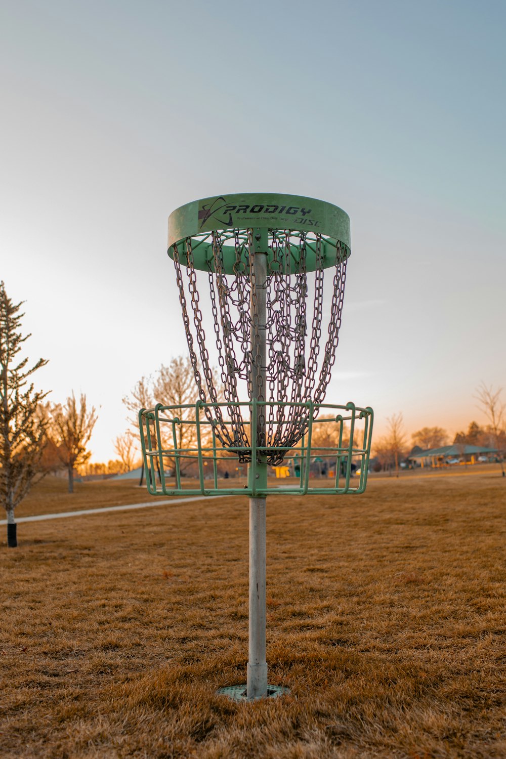 a green frisbee golf basket in a field
