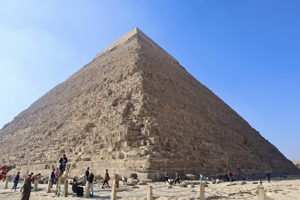 a group of people standing in front of a large pyramid