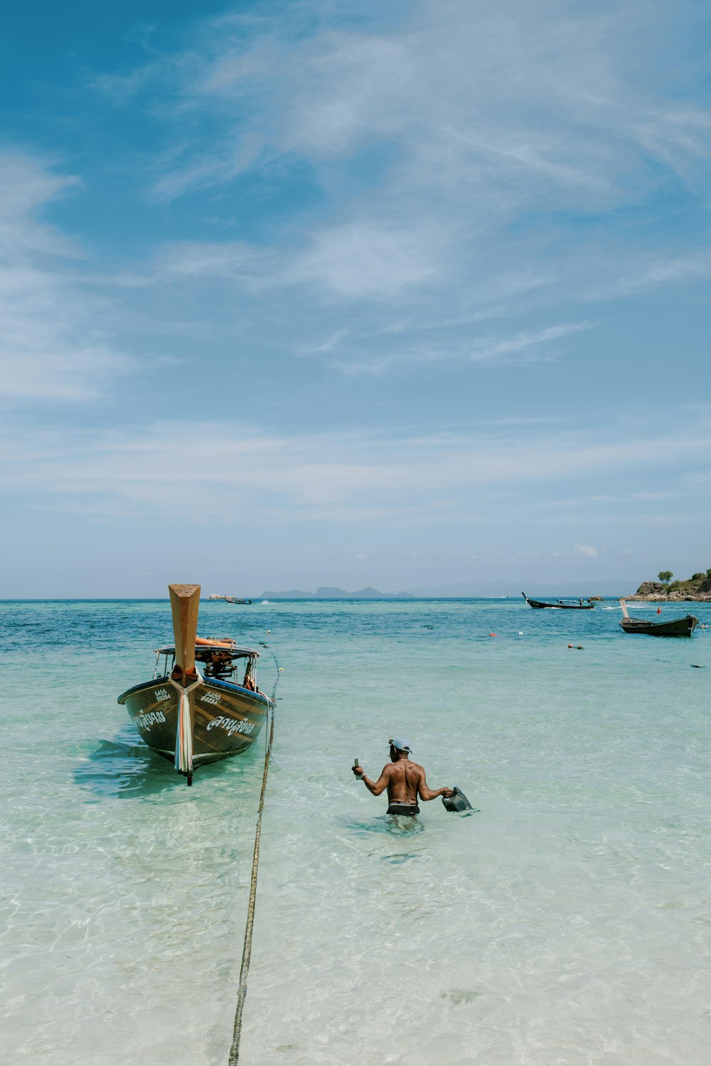 a man standing in the ocean next to a boat