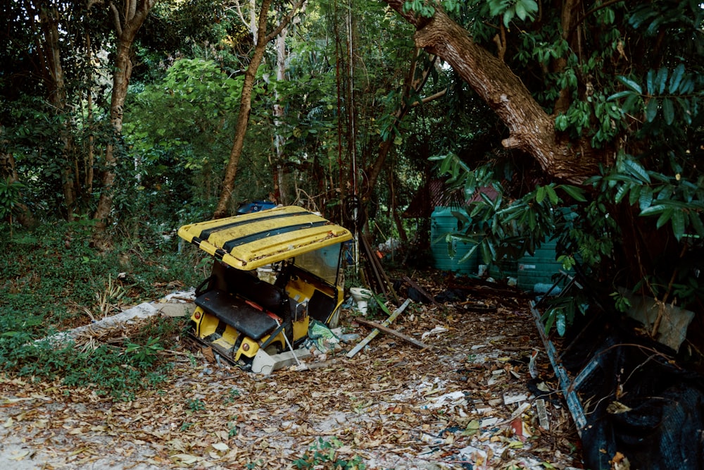 a yellow and black vehicle parked in the middle of a forest
