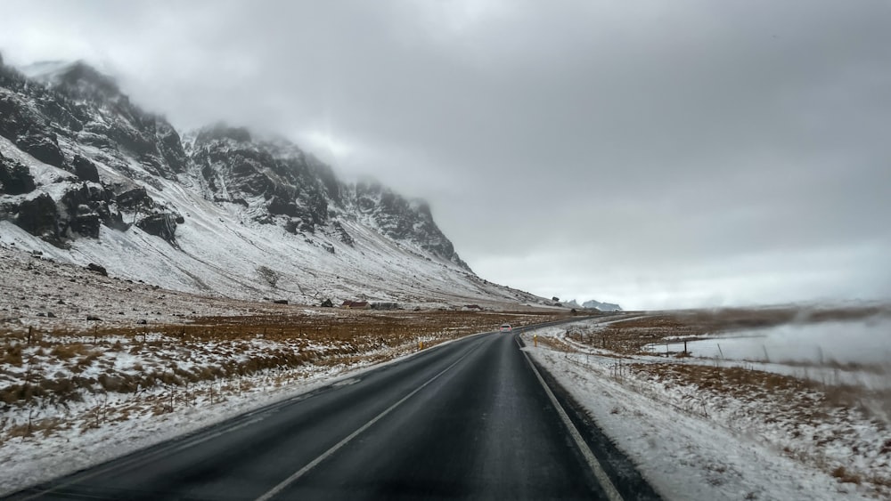 a snowy road with a mountain in the background