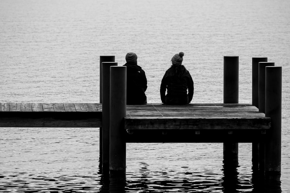 Un par de personas sentadas en lo alto de un muelle