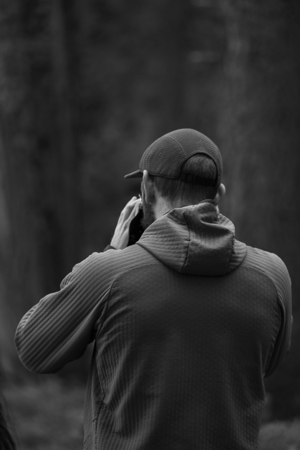 a man standing in a forest talking on a cell phone