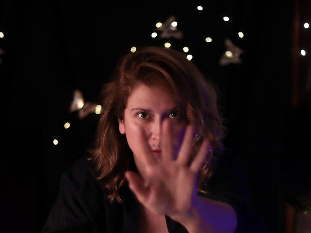a woman making a hand gesture in the dark