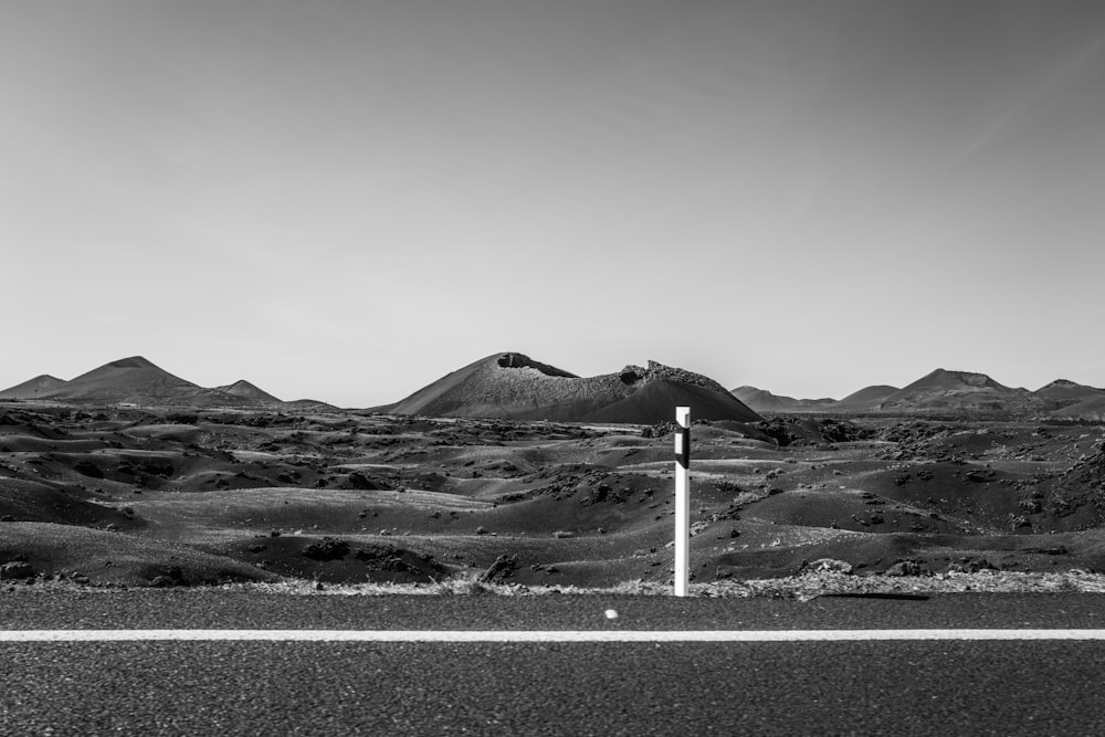 a black and white photo of mountains and a street sign