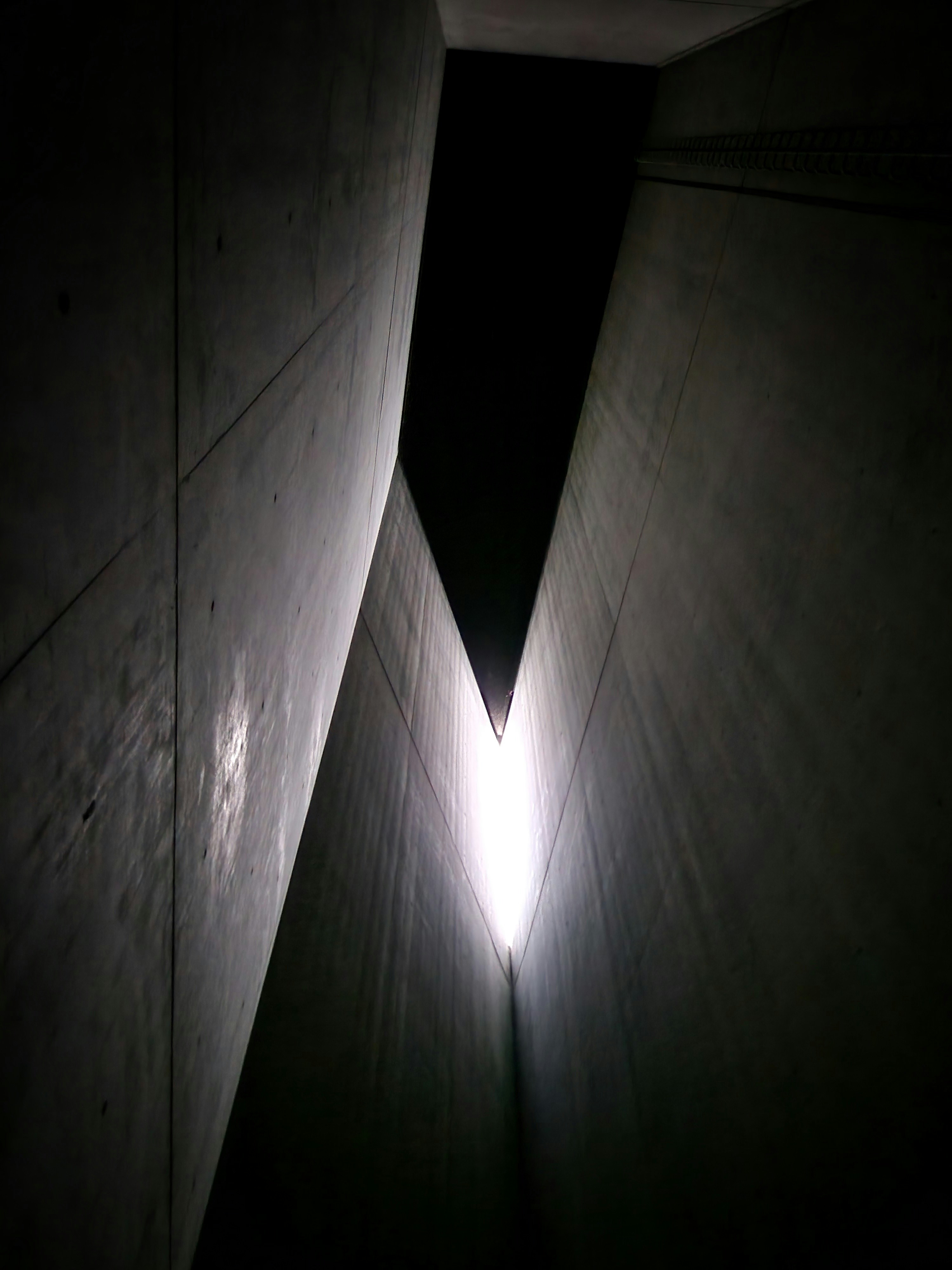 Dramatic architectural interior with sweeping concrete staircase and a single beam of natural light