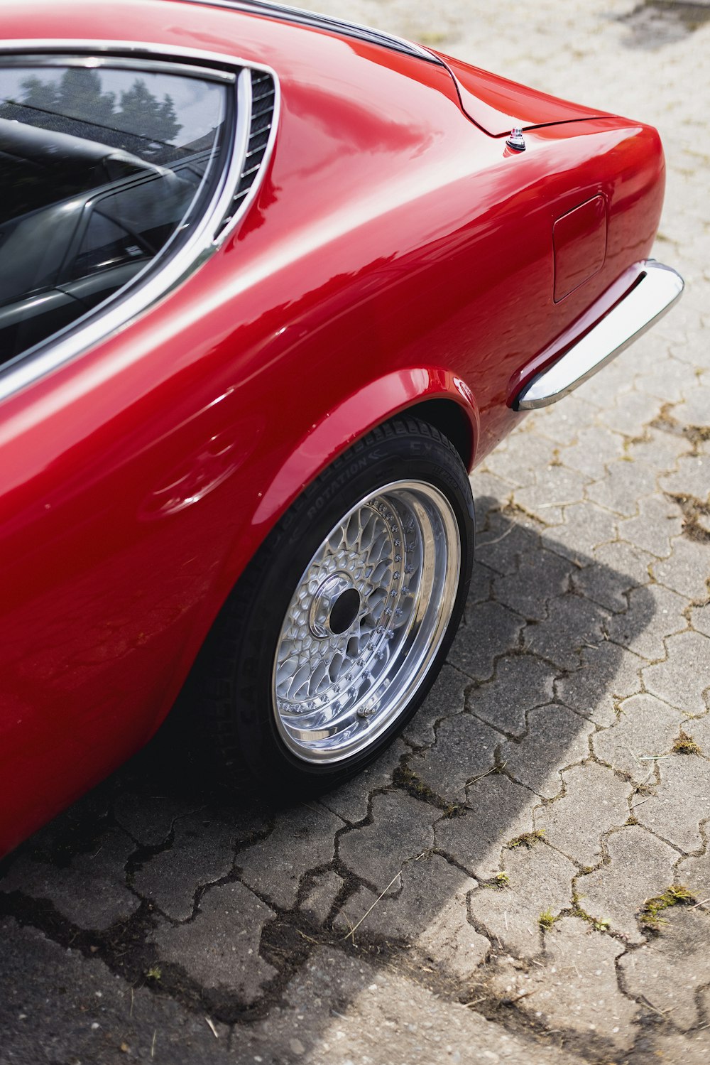 a red sports car parked on a cobblestone street