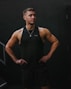a man in a black tank top is standing with his hands on his hips