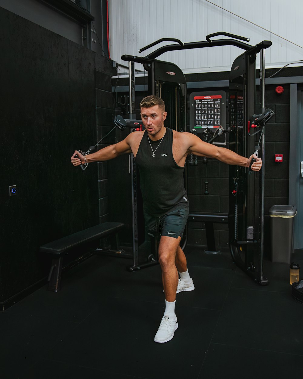 a man in a black tank top is doing exercises in a gym