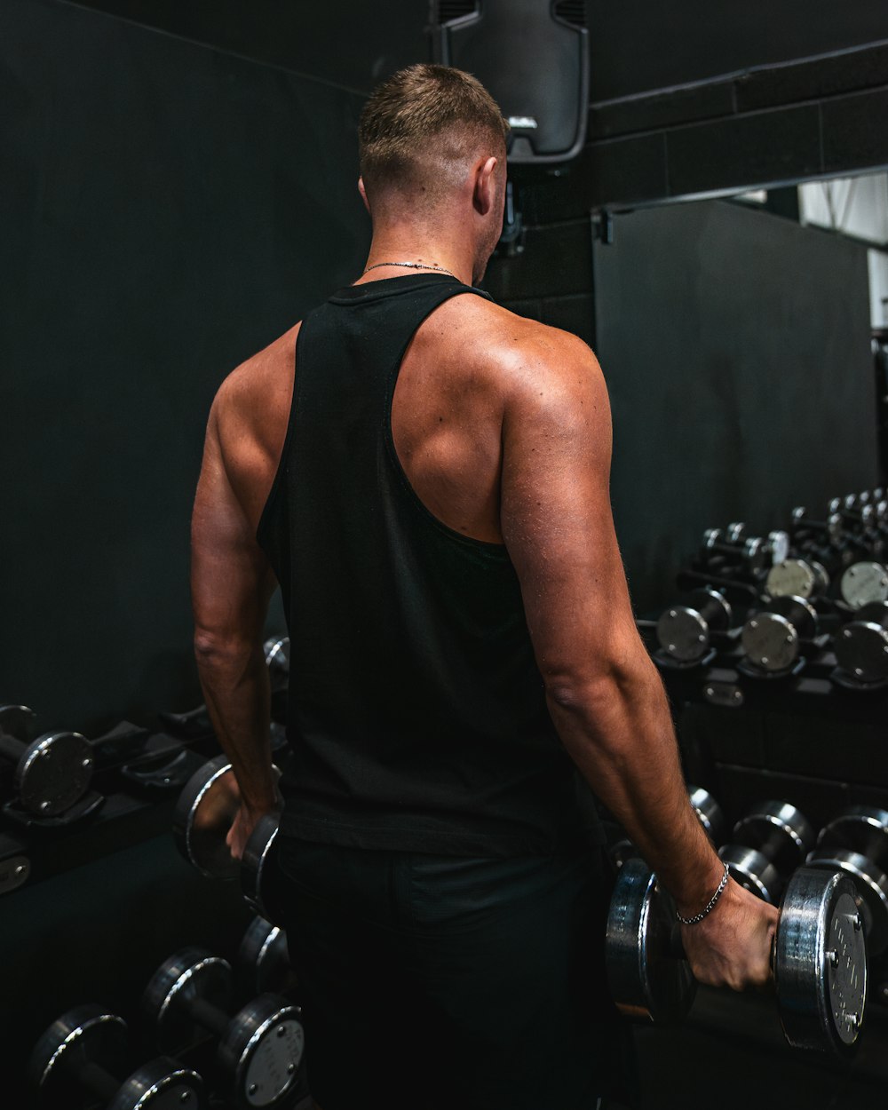 a man holding a pair of dumbs in a gym