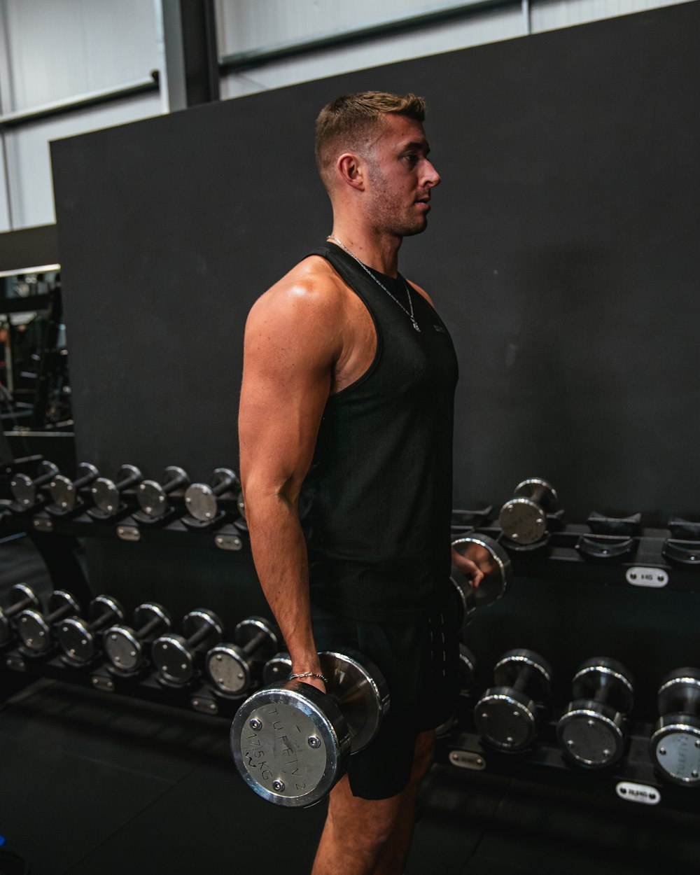 a man holding two dumbs in a gym