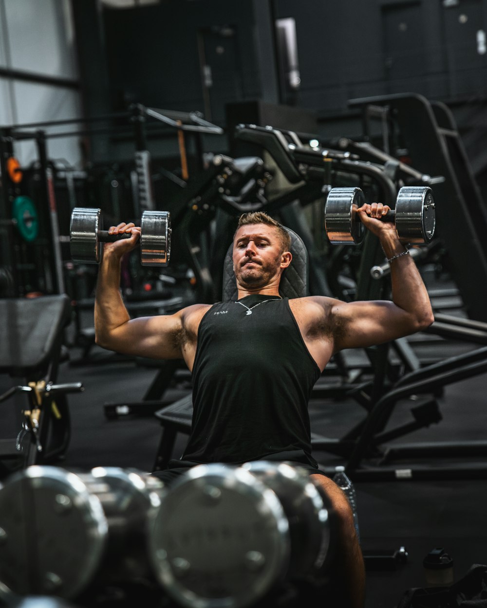 a man in a gym holding two dumbbells