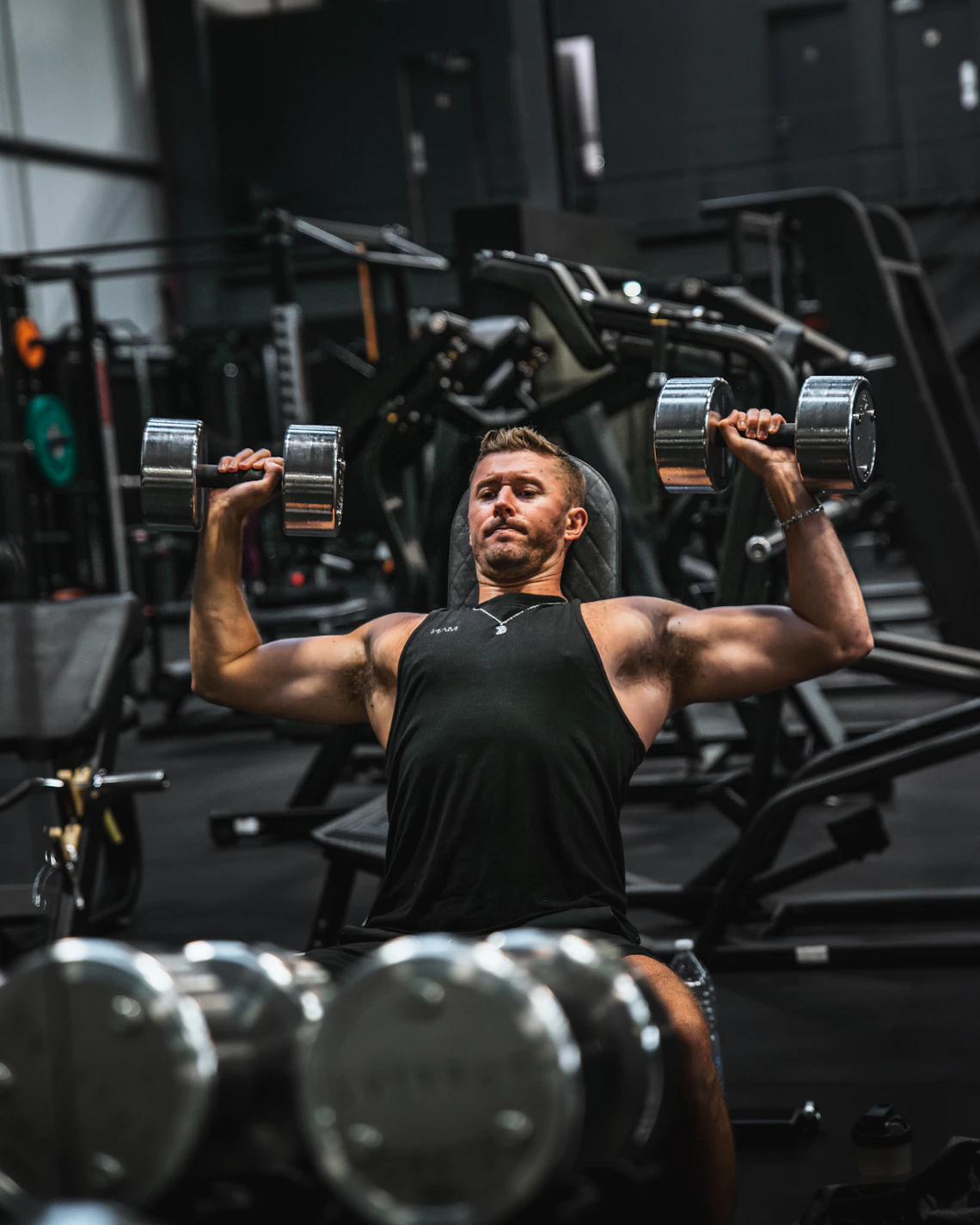 Athlete performing a controlled dumbbell press in a professional gym
