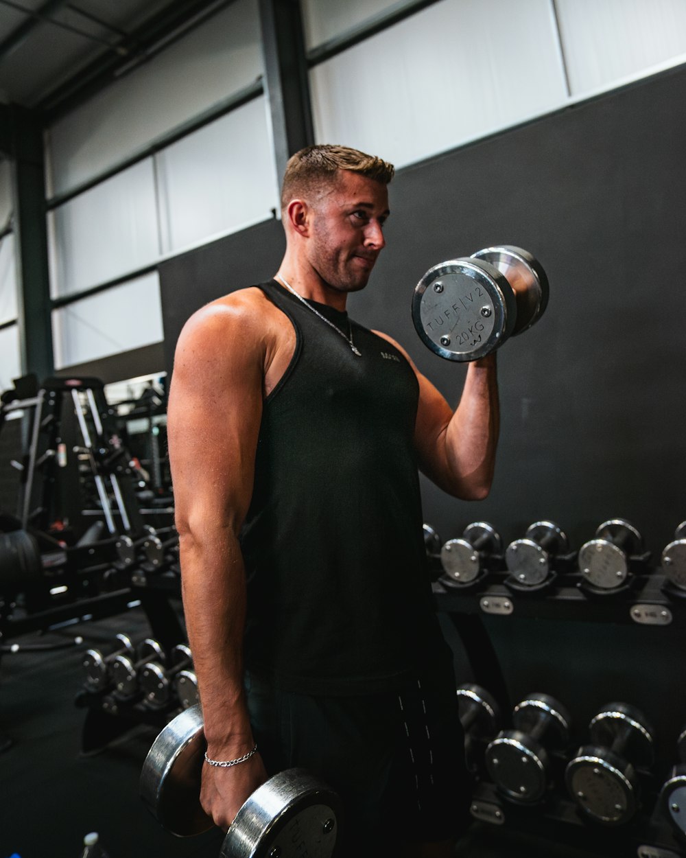 a man holding two dumbs in a gym