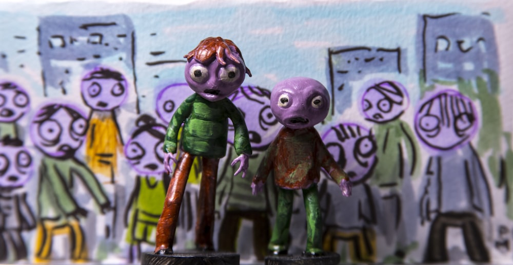 a couple of figurines that are standing in front of a wall