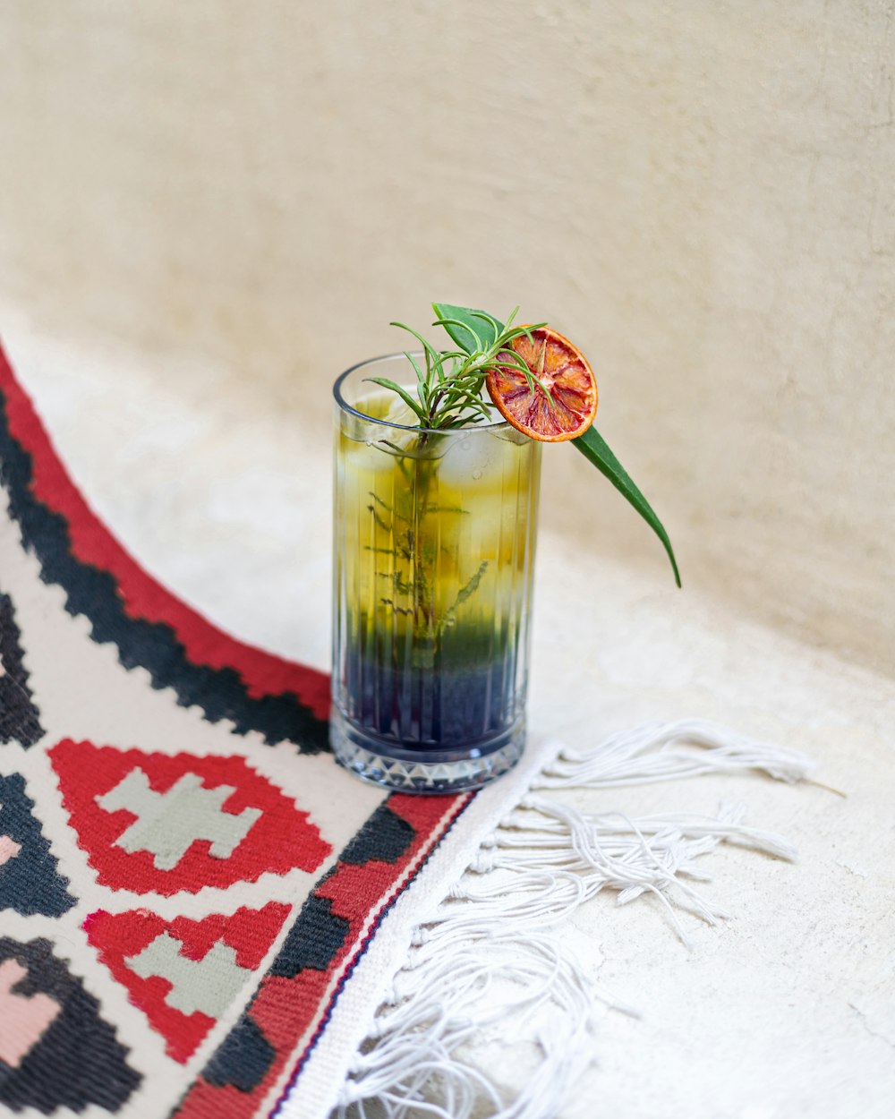 a tall glass filled with a drink sitting on top of a rug