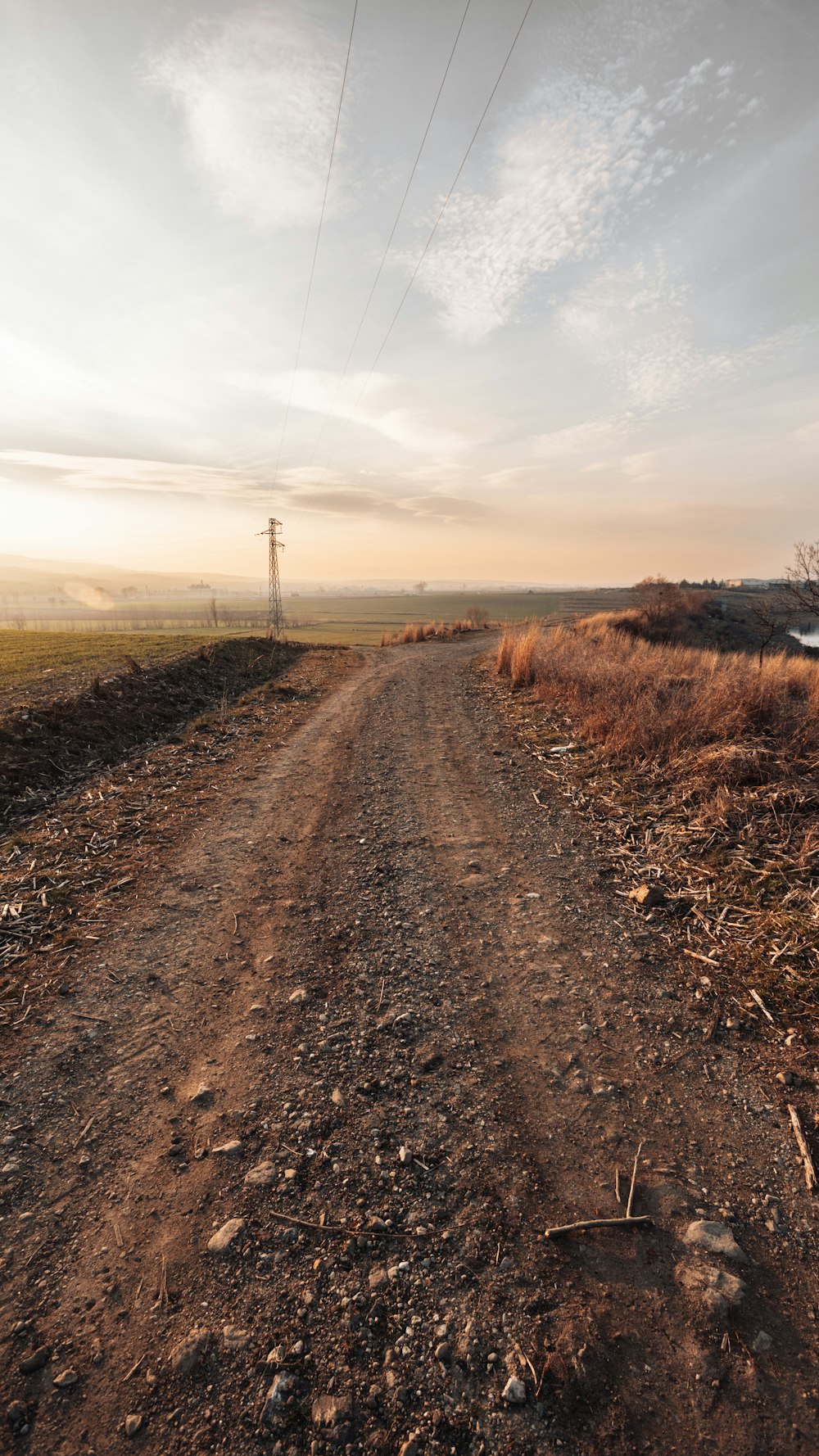 a dirt road with a telephone pole in the distance