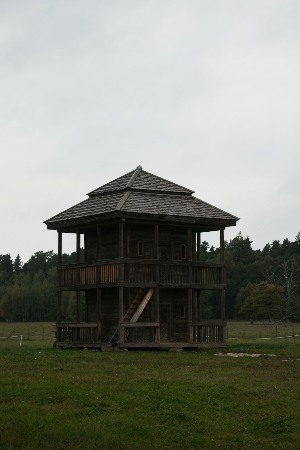 a tall wooden structure sitting on top of a lush green field