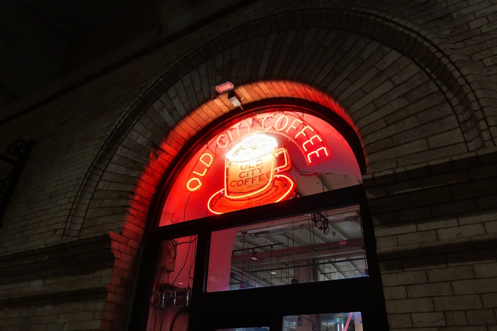 a red neon sign above a window of a coffee shop