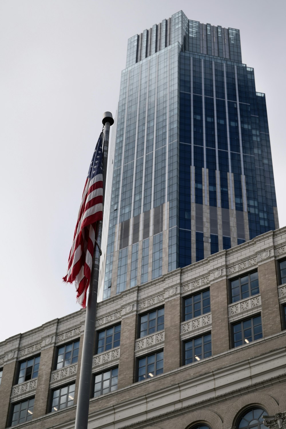 Una bandera estadounidense ondeando frente a un edificio alto