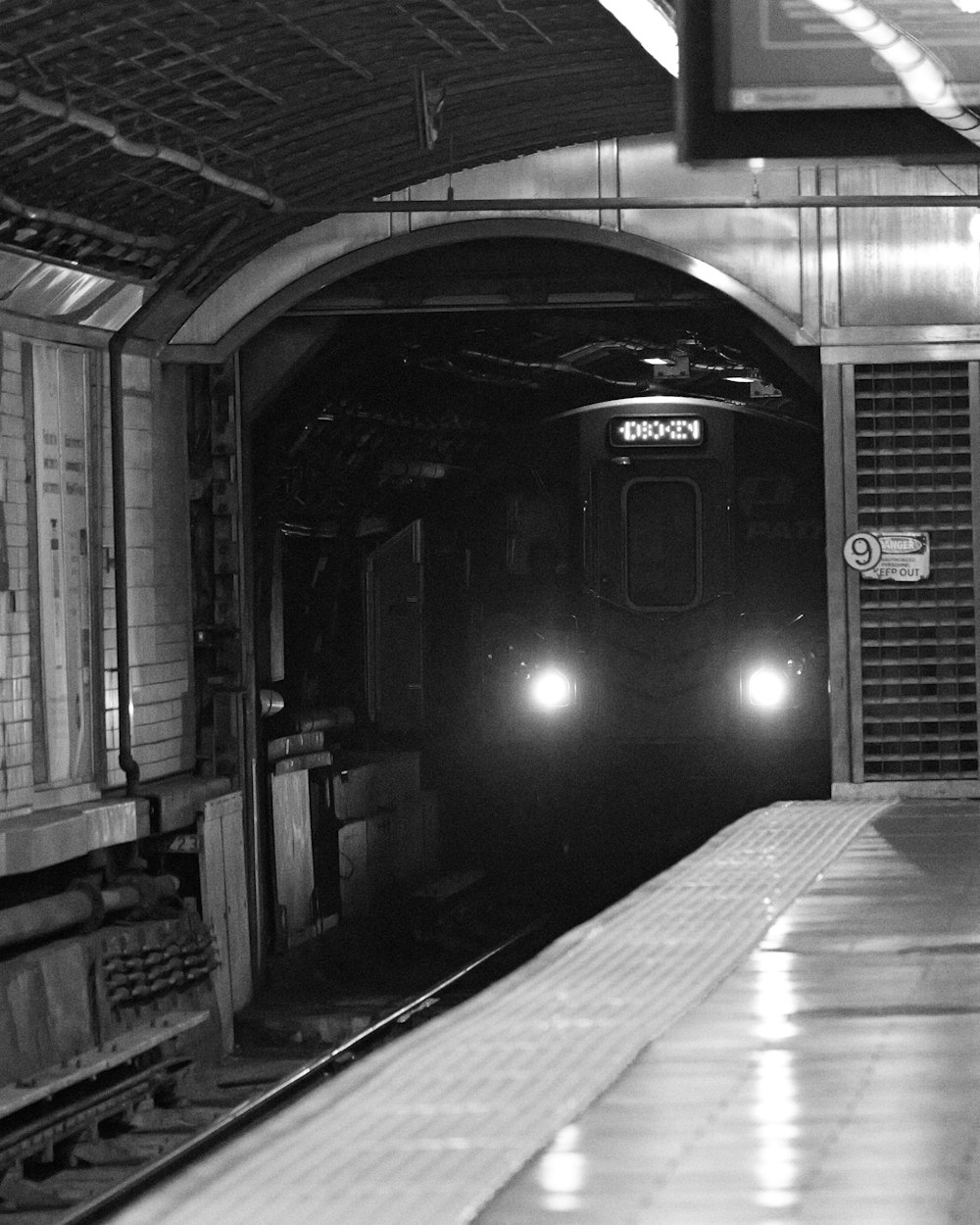 una foto in bianco e nero di un treno che esce da una galleria
