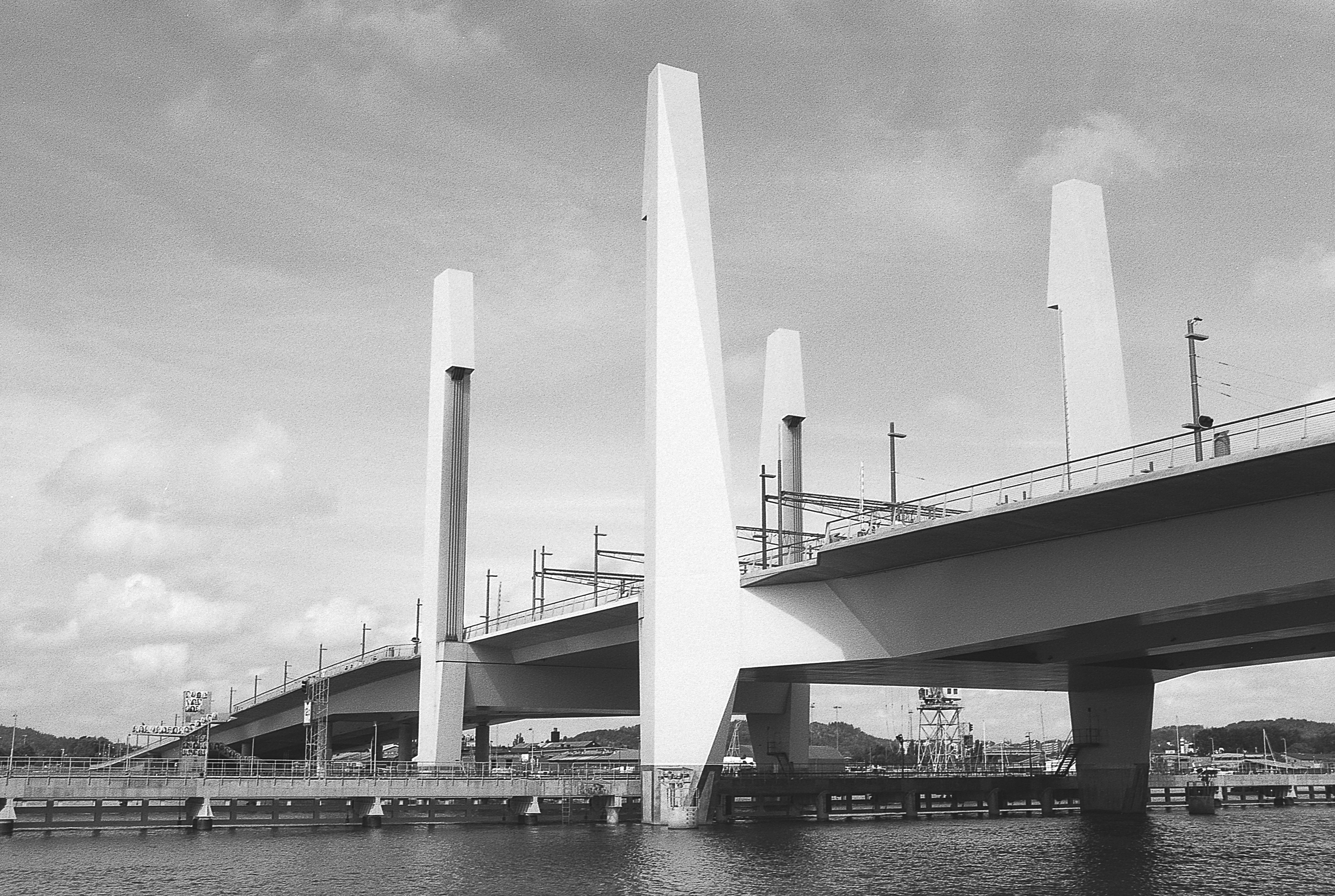 a black and white photo of a bridge over water, 