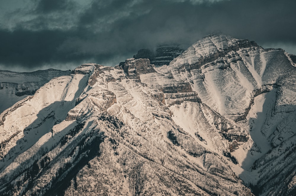 a mountain covered in snow under a cloudy sky