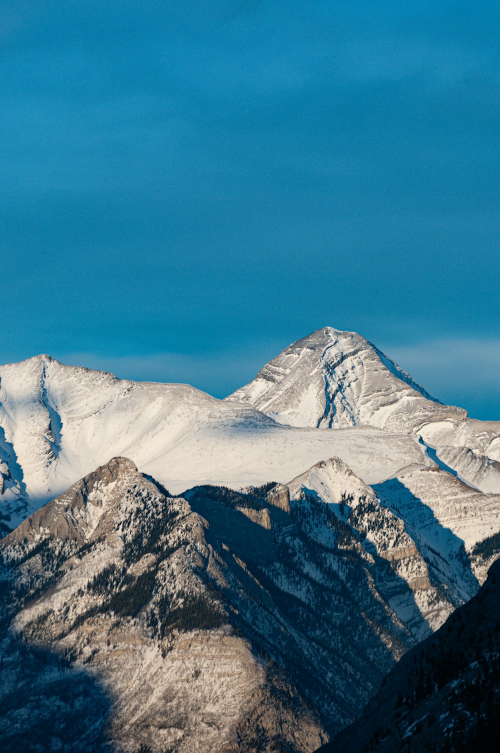 a snow covered mountain range under a blue sky